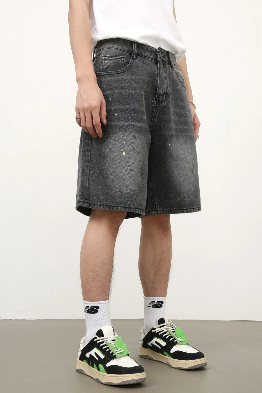 Dark wash denim bermuda shorts with paint splatter detail and relaxed fit.