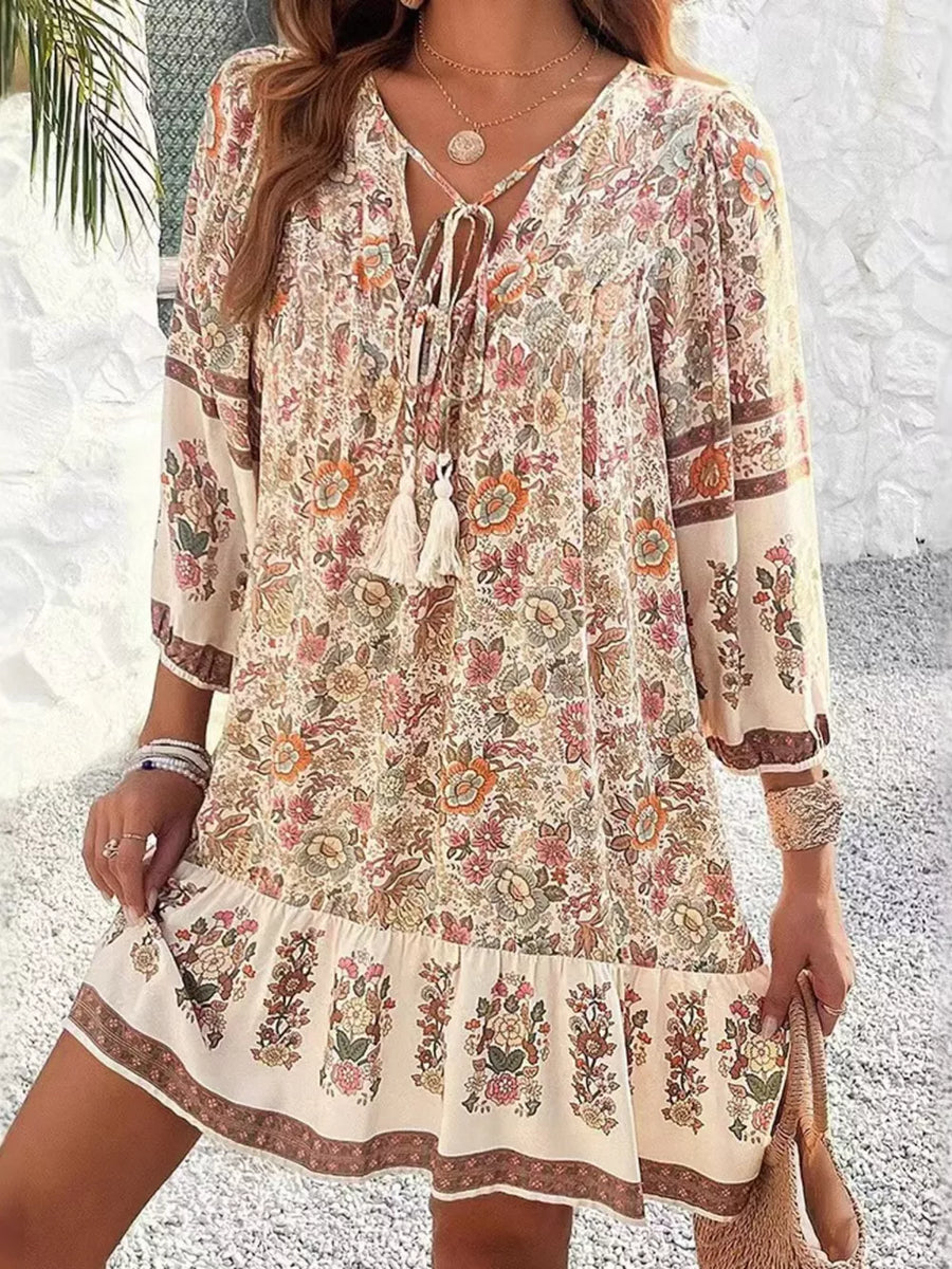 Vibrant floral tassel tie mini dress with tiered hem and peasant sleeves.