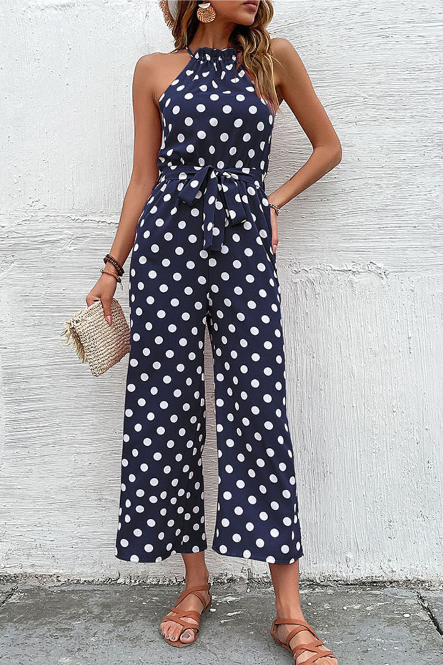 Navy polka dot halter neck palazzo jumpsuit with tie waist and wide legs.