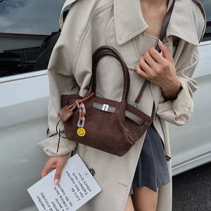 Elegant coffee brown suede and leather mini tote bag with smiley charm and chain detail.