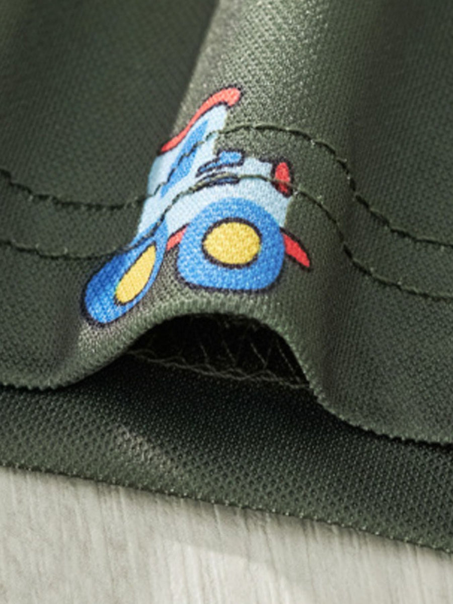 Children's green polo shirt with a blue tractor print detail.