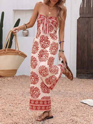 Charming floral tie-front wide-leg romper in cream with red print, strapless neckline, and flowy legs.