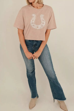 Beige cotton crew neck tee with horseshoe lace and pearl accent.
