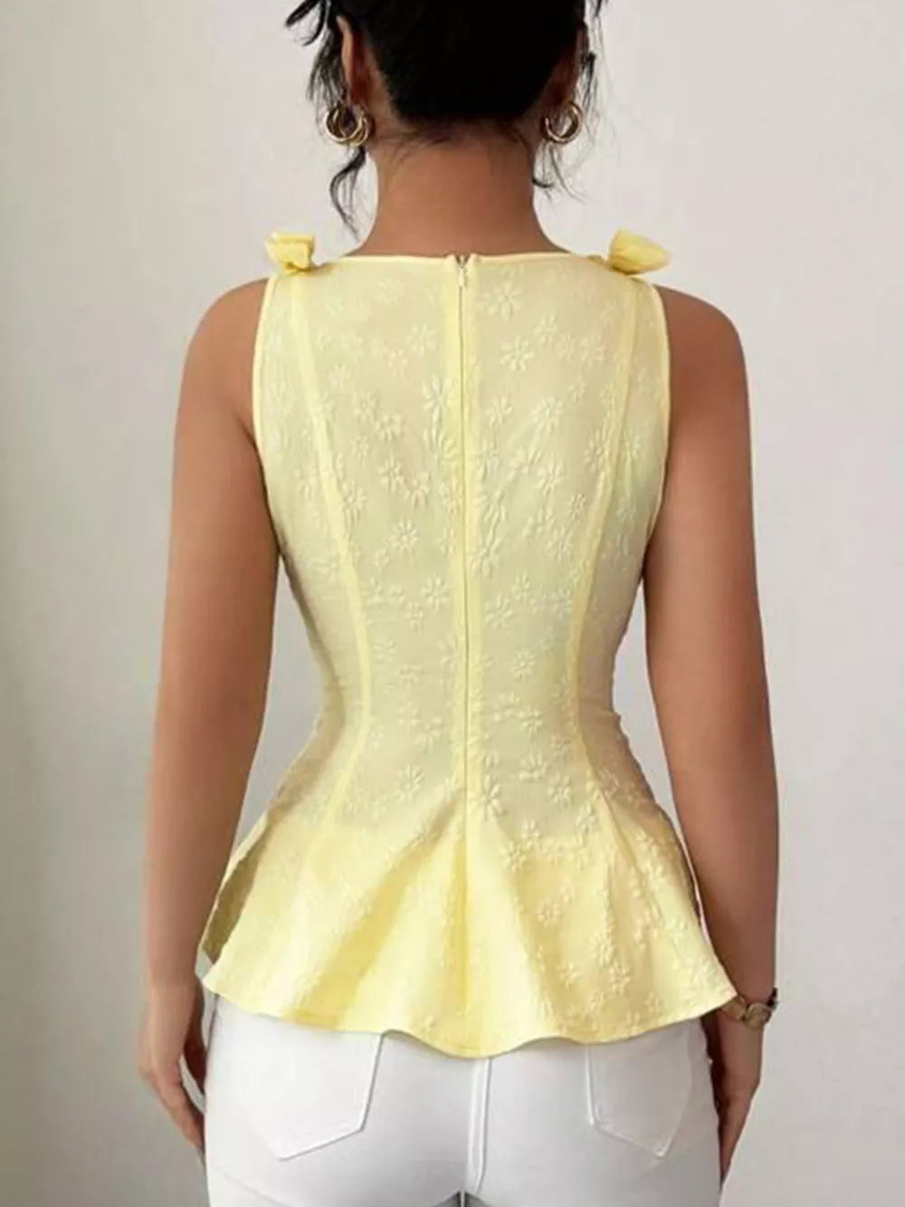 Yellow peplum tank top with bow shoulder details and floral texture.