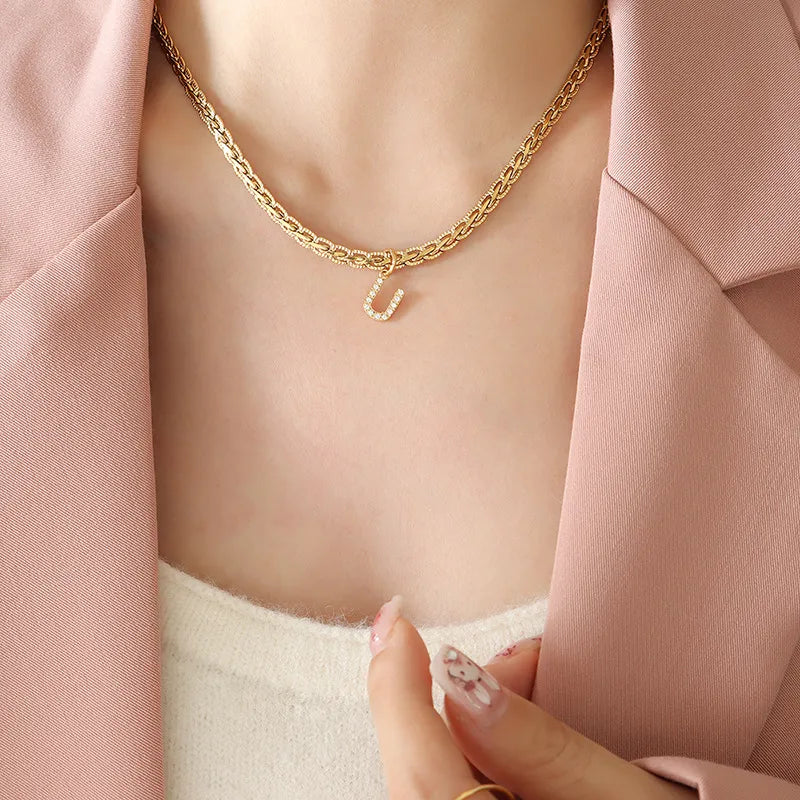 Gold textured chain necklace with a diamond-encrusted initial U charm.