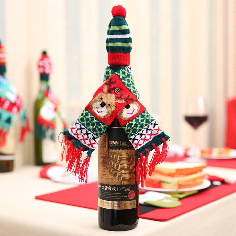 Knit bottle cosy with reindeer face scarf and striped hat, red tassels.