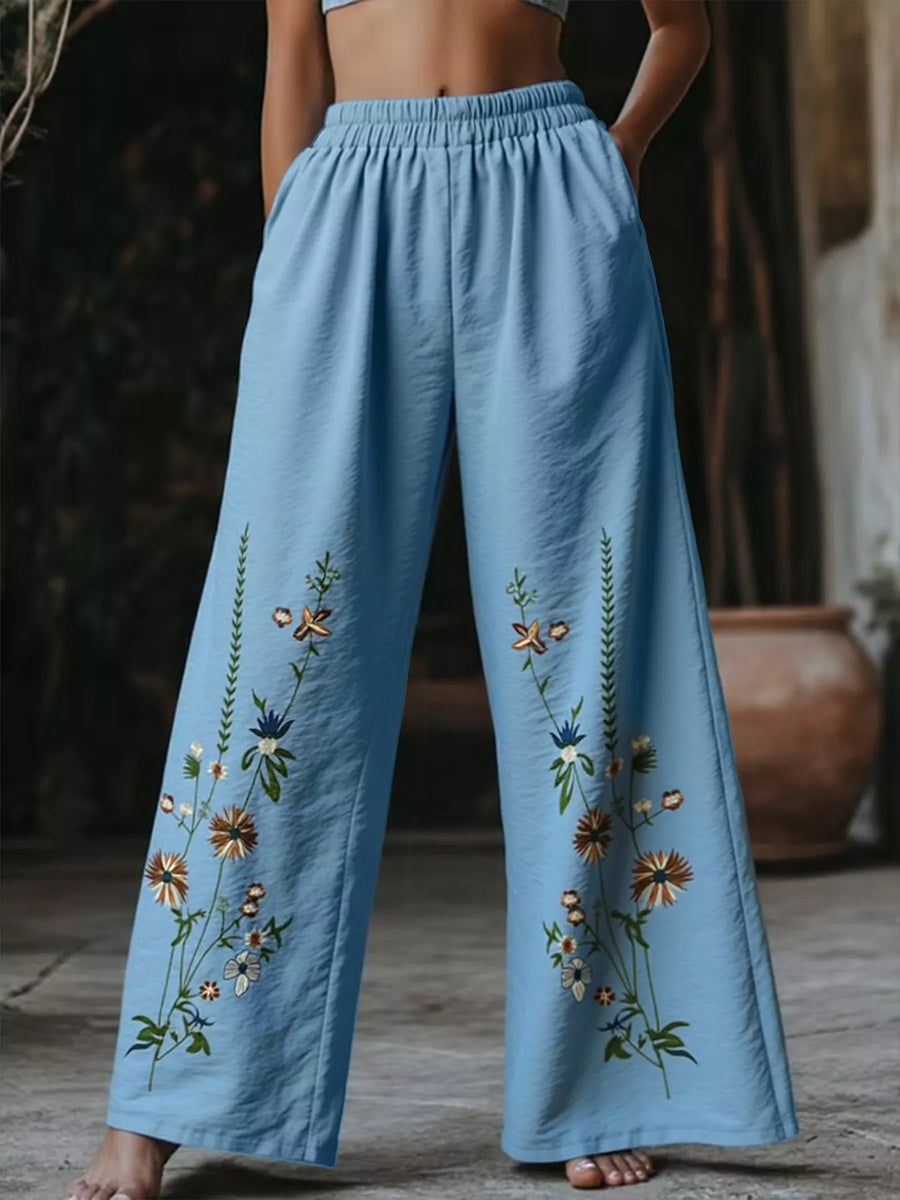 Sky blue wide-leg trousers with embroidered floral details and elastic waist.