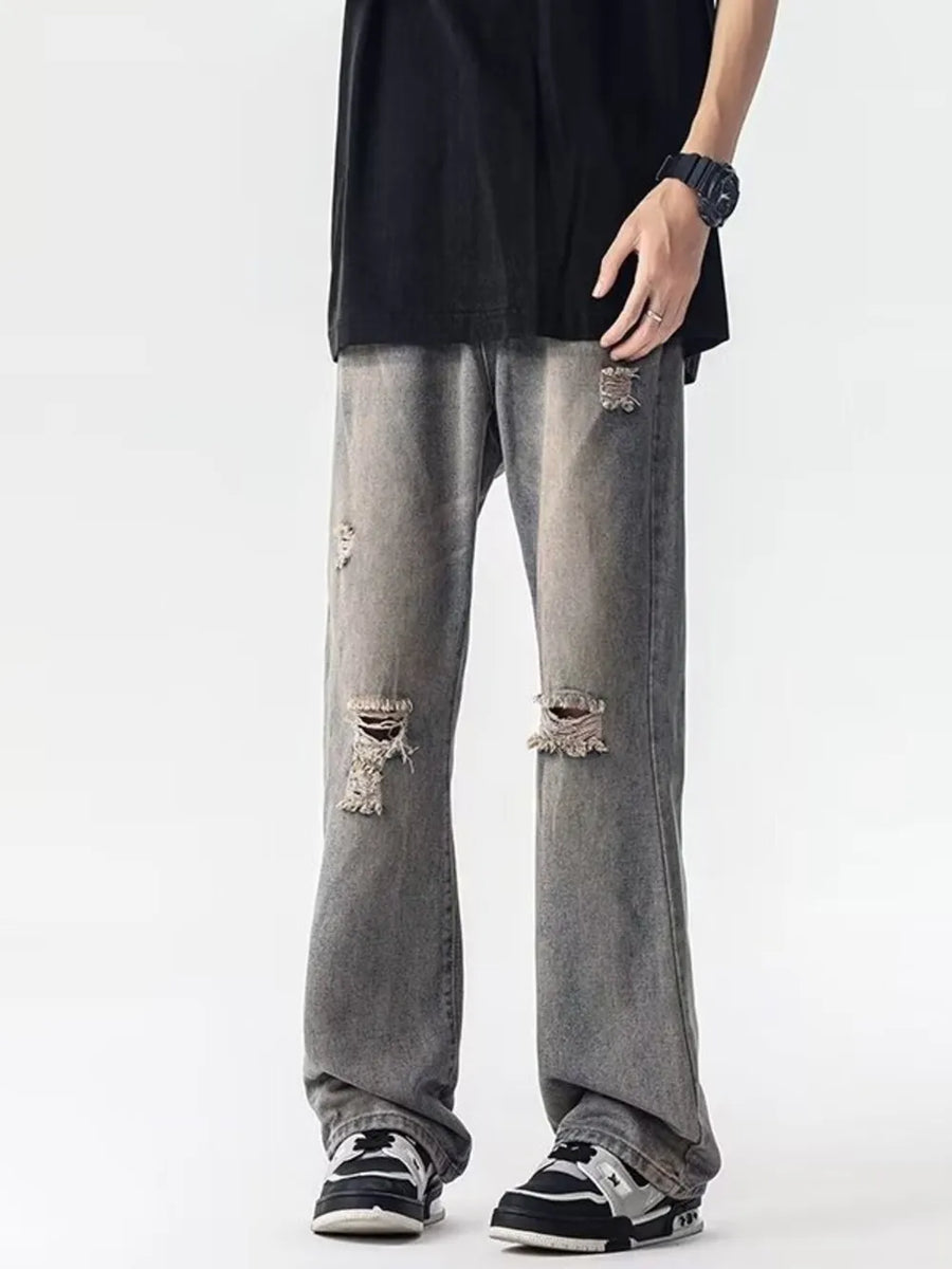 Men's grey loose fit jeans with distressed details and rips.