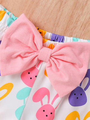 Baby set with pink bow and colorful bunny print on white fabric.