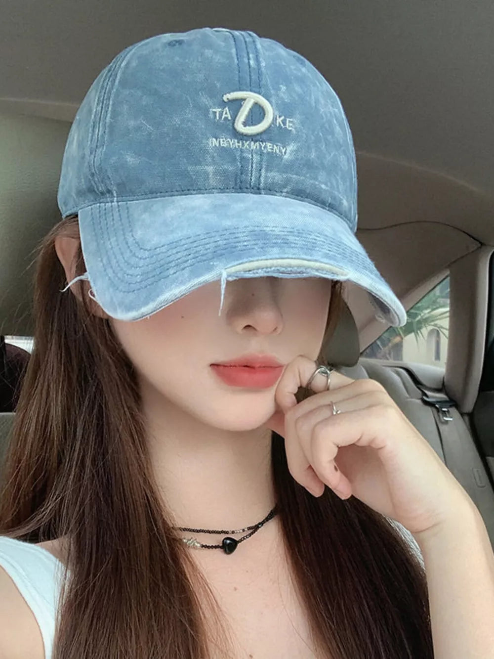 Blue denim baseball cap with distressed brim and white embroidery detail.