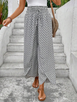 White and black patterned palazzo pants with a smocked waist and drawstring detail.