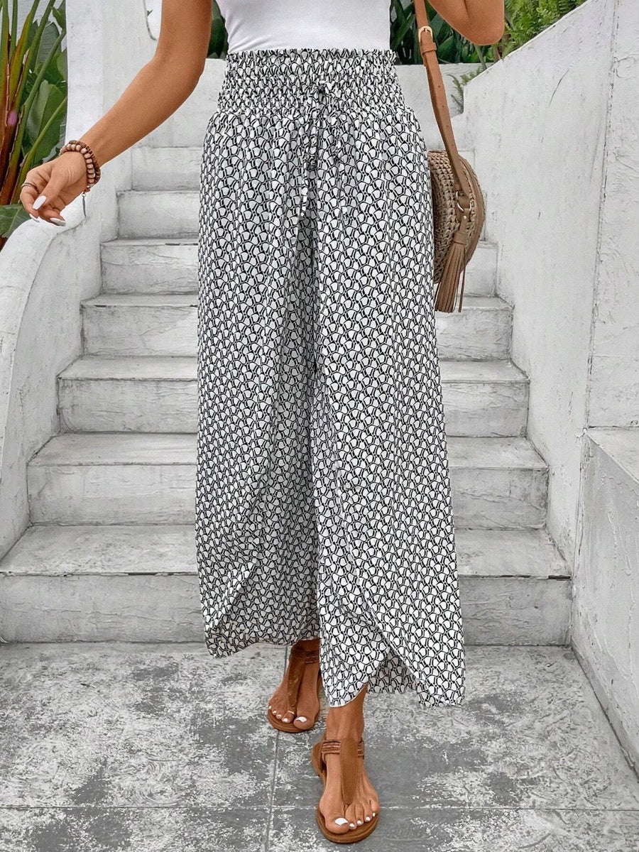 White and black patterned palazzo pants with a smocked waist and drawstring detail.