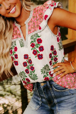 Vibrant floral cotton blouse with ruffled trim and notched neckline, styled with denim shorts.