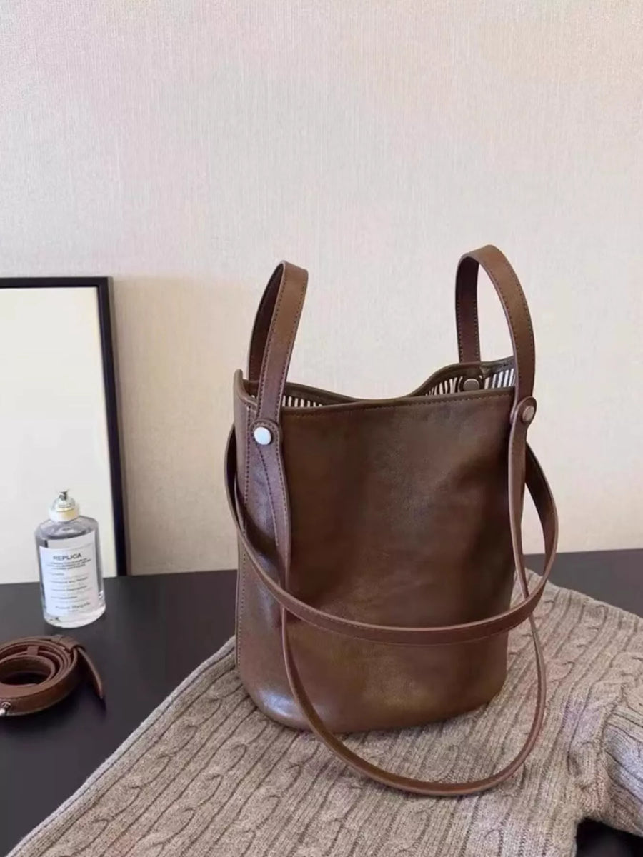 Coffee brown PU leather bucket bag with top handles and a crossbody strap.