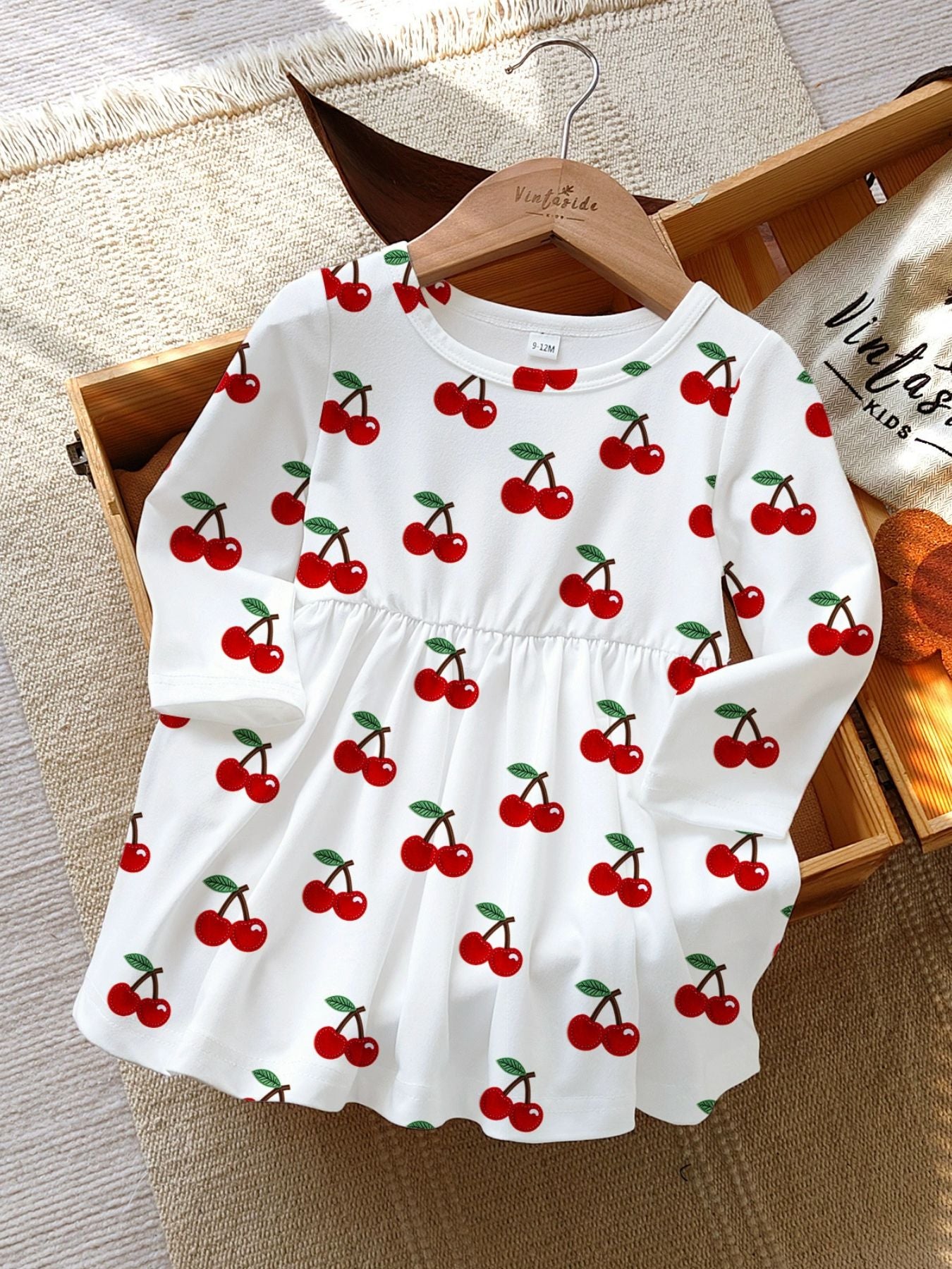 White long sleeve baby dress with allover red cherry print and gathered waist