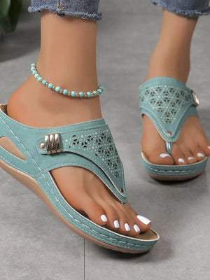 Turquoise laser-cut thong sandals with decorative buckle detail and white stitching.