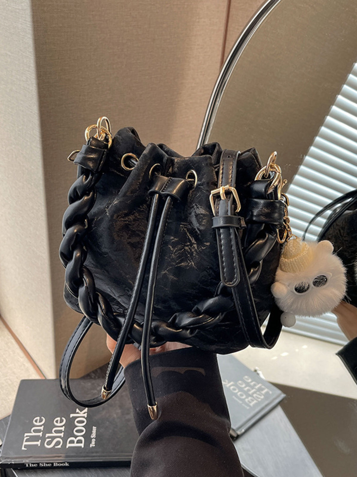 Black bucket bag with chunky chain trim and fuzzy charm