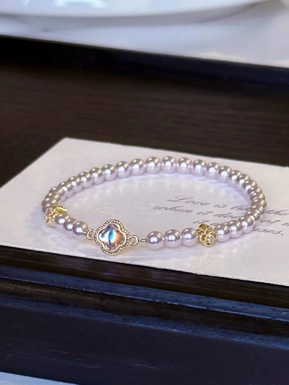 Delicate pearl bracelet with clover charm and gold accents