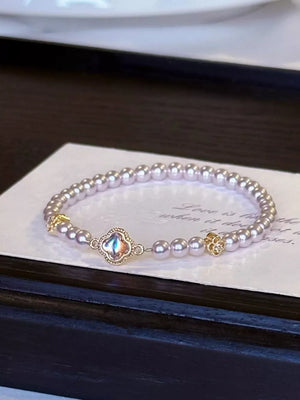Delicate pearl bracelet with clover charm and gold accents