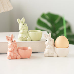 Ceramic bunny egg holders in blush pink, ivory, and light green.
