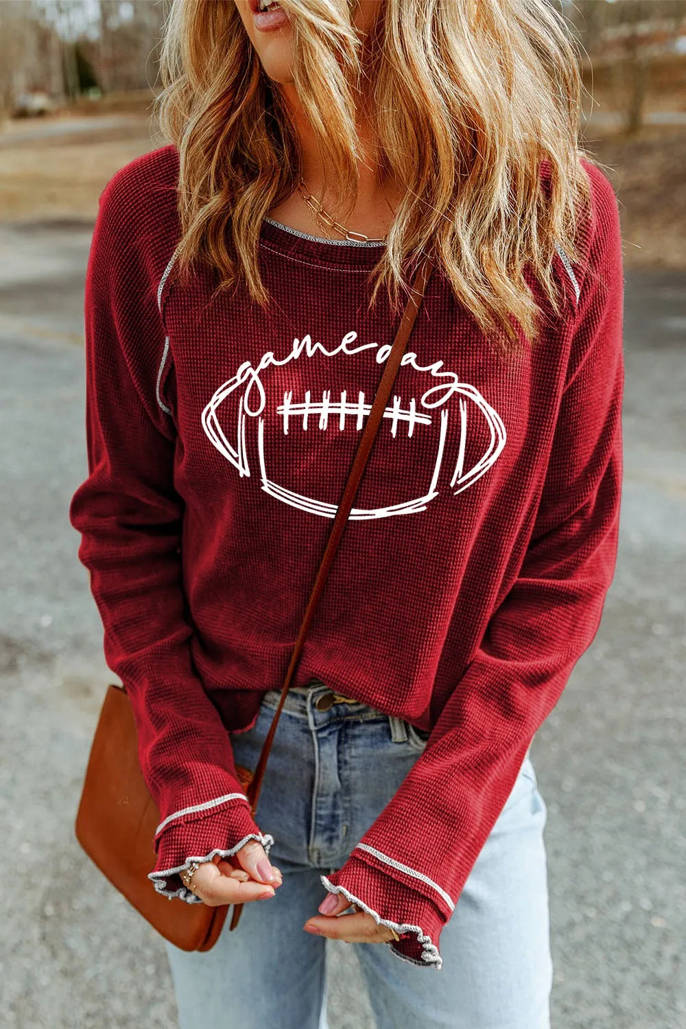 Burgundy waffle knit crewneck top with "Game Day" football graphic and ruffled cuffs.