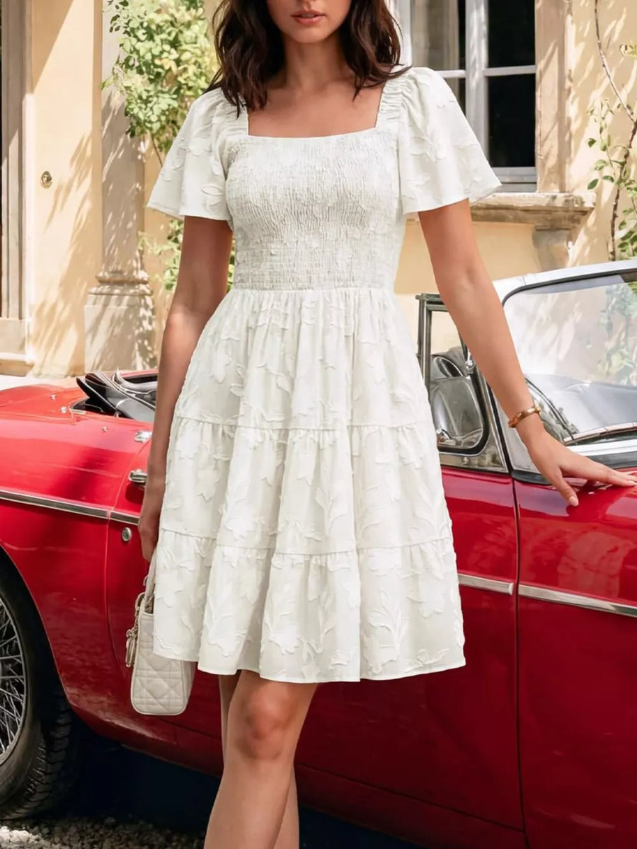 White smocked mini dress with tiered skirt and puff sleeves.