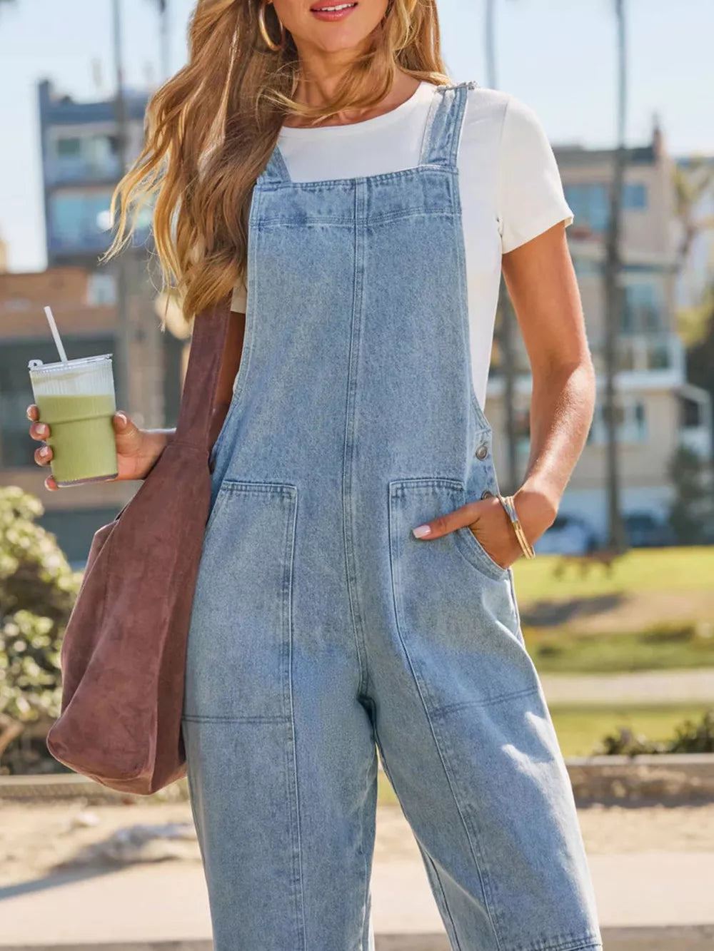 Light wash denim overalls with wide legs and large front pockets.