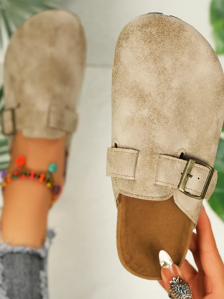 Beige textured suede cork mules with buckle detail and adjustable strap.