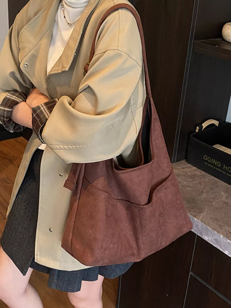 Large brown suede shoulder bag with exterior pockets.
