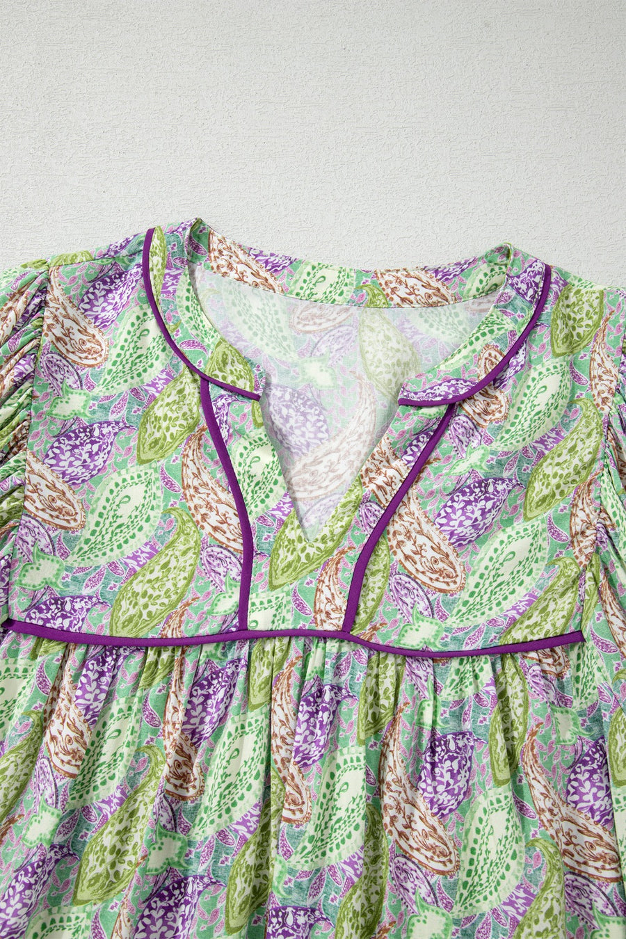 Paisley print puff sleeve blouse with purple trim and V-neck.