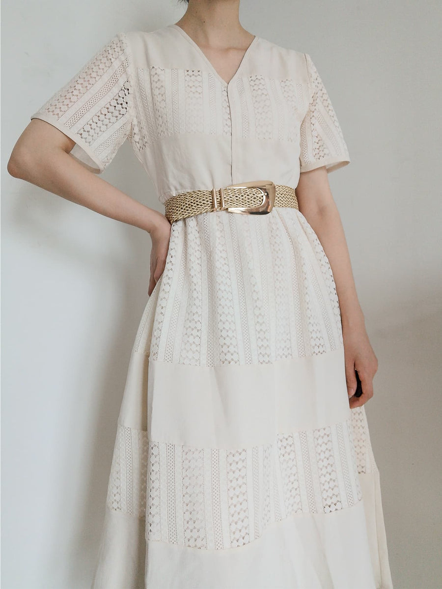 Woven raffia belt with gold-tone buckle, cinching a white lace dress.