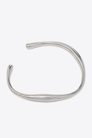 Sculpted silver open-ended bangle with a chic, fluid design.