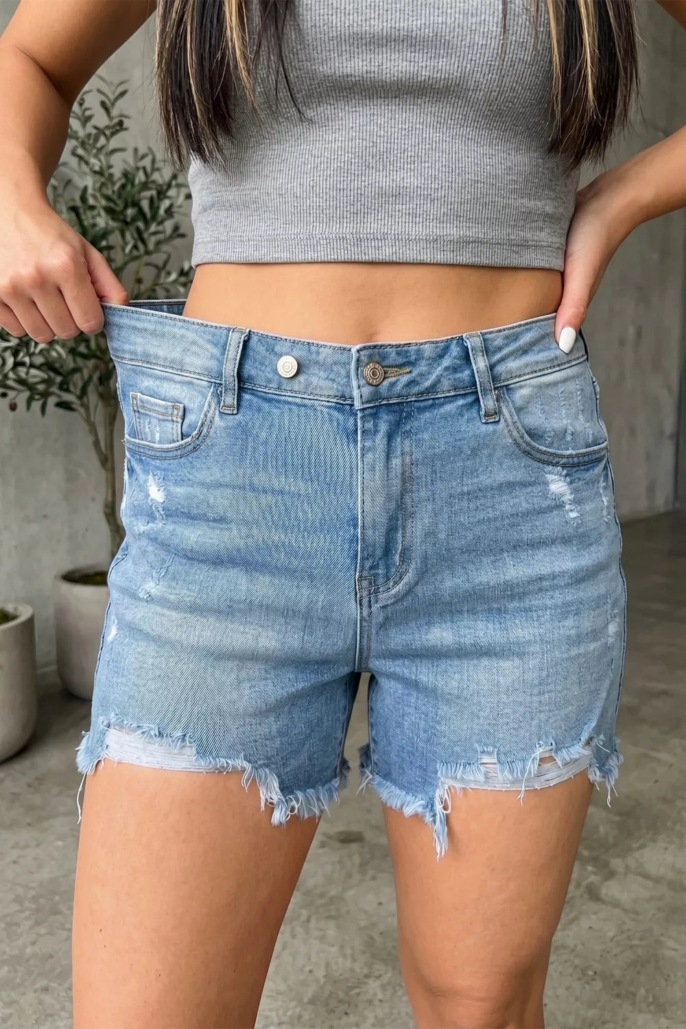 Light wash denim shorts with whiskering, distressed details, and raw hem.