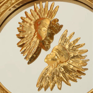 Gold sculptural sunburst earrings with textured petals and a face detail.