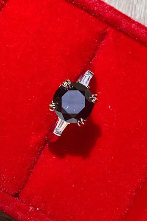 Black moissanite solitaire ring with baguette accents on a silver band.