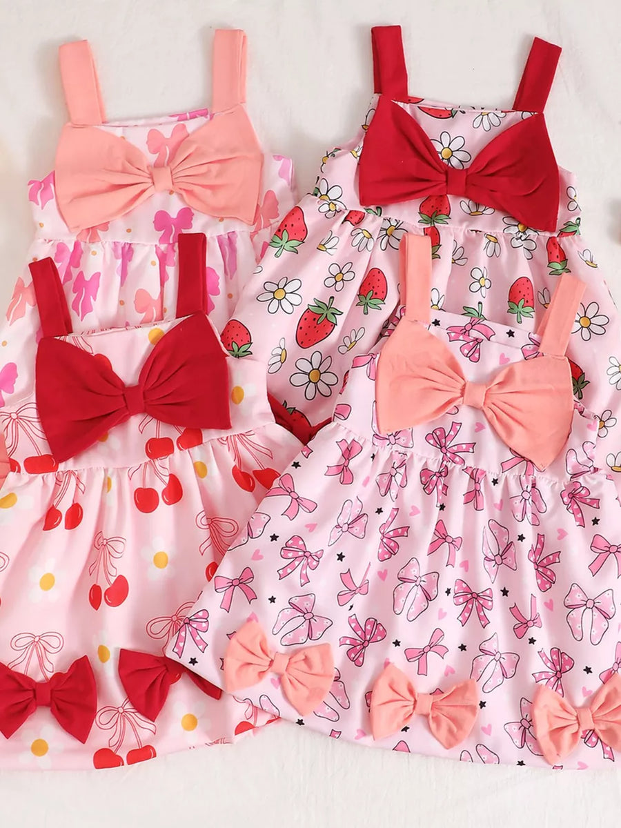 Baby dresses with bow details in pink, strawberry, red, and purple prints.