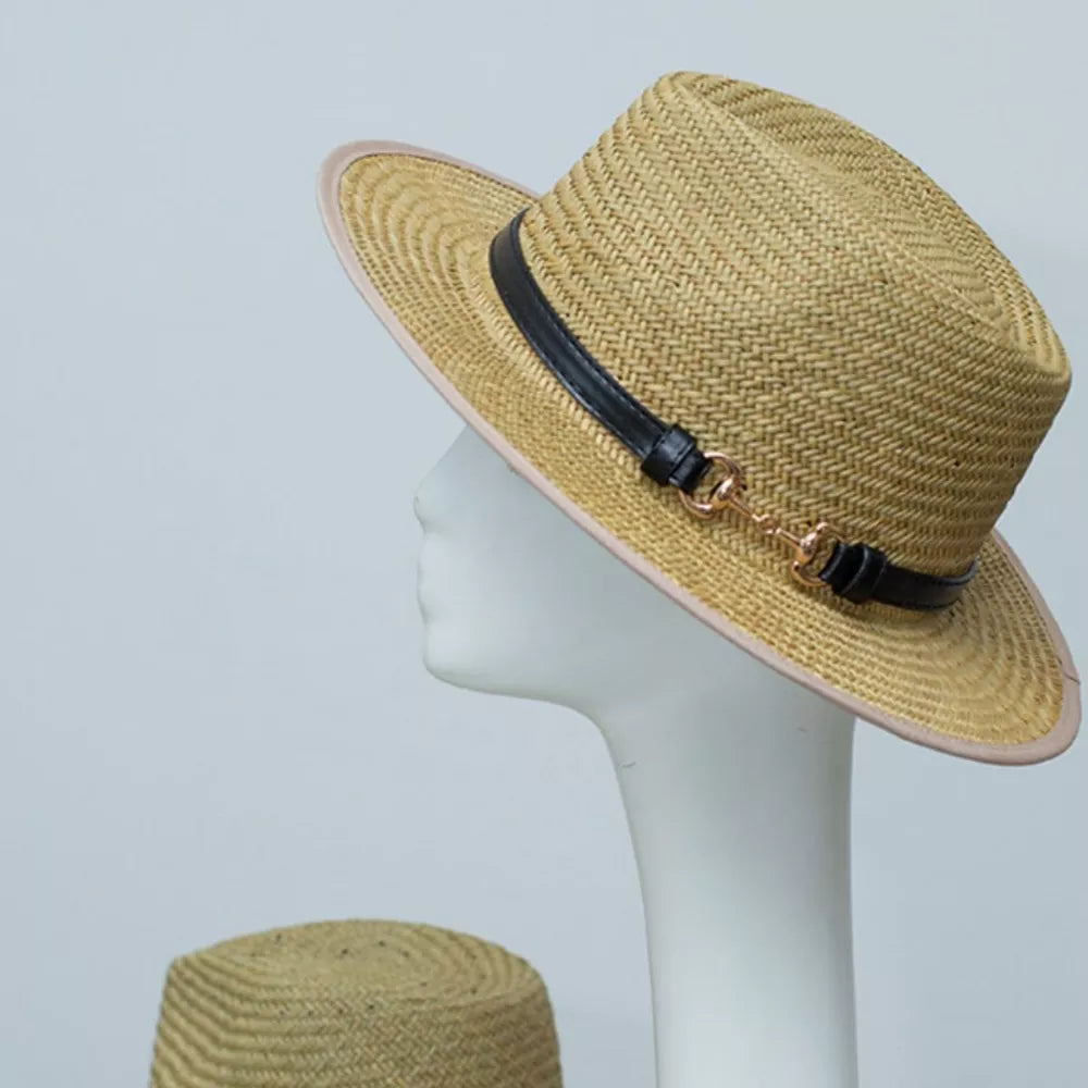 Woven straw fedora hat with black decorative band and gold buckle detail.