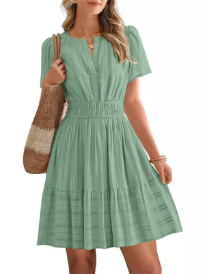 Light green textured V-neck tiered dress with smocked waist and short sleeves.