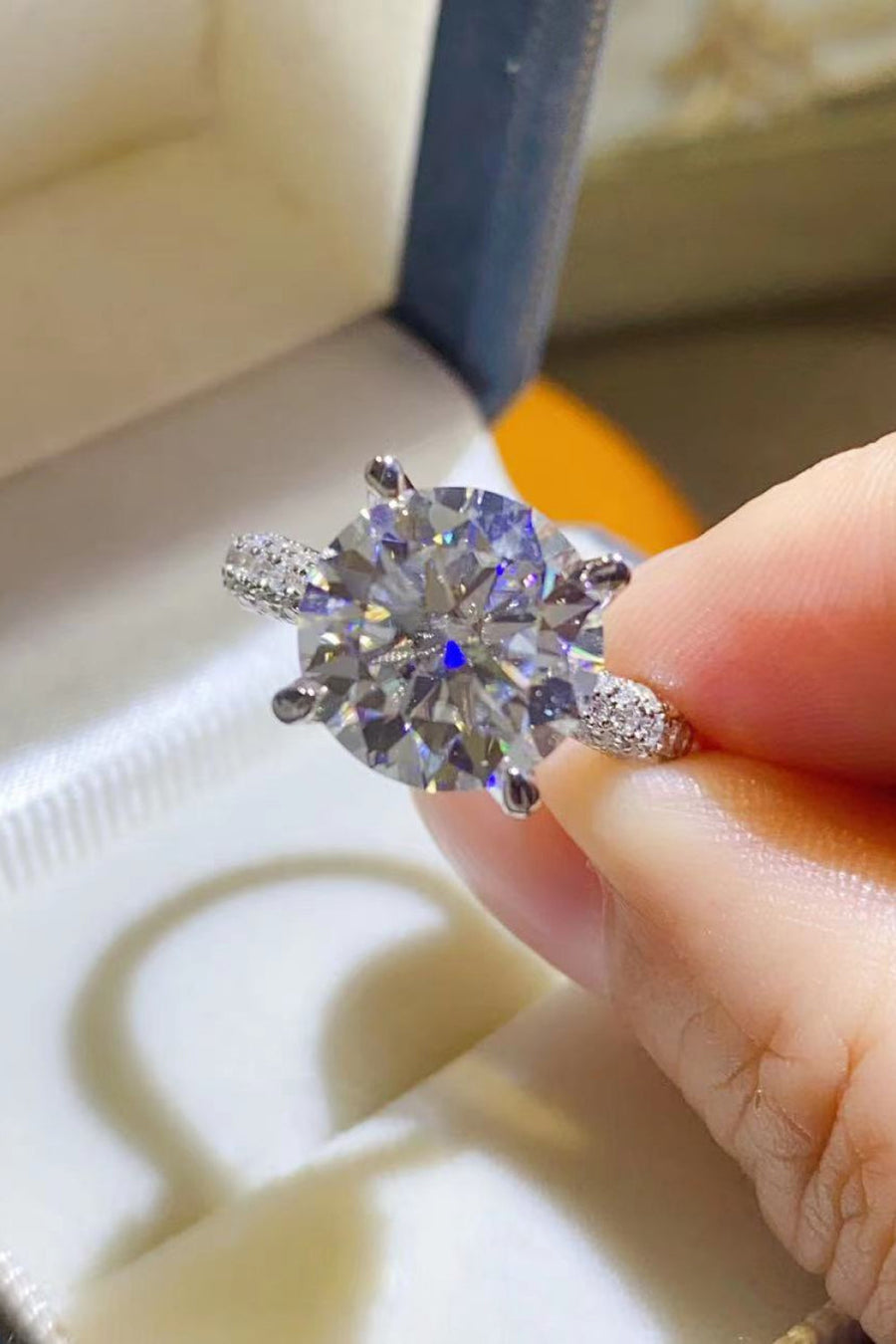Silver pavé band round moissanite solitaire ring with a large center stone.