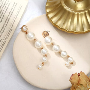 Gold cascading pearl drop earrings with multiple pearl sizes.