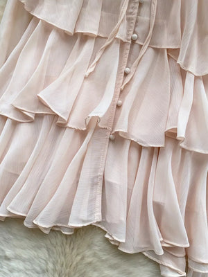 Pink chiffon blouse with tiered ruffles and button-down detail.