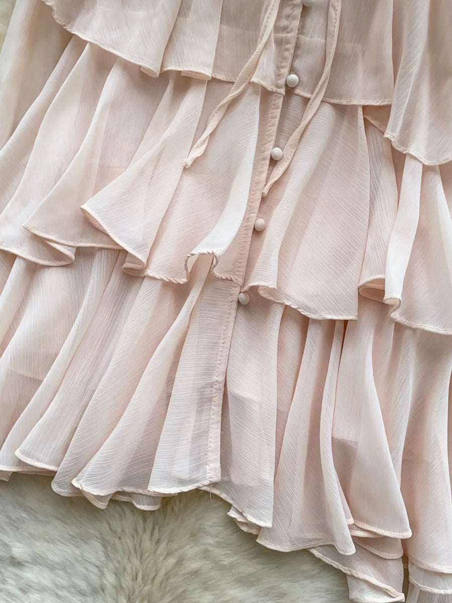 Pink chiffon blouse with tiered ruffles and button-down detail.