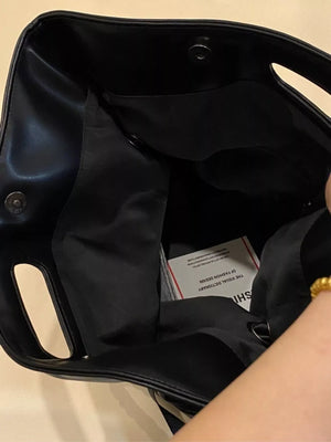 Black oversized PU leather tote bag interior with snap closure and a fashion dictionary tag.