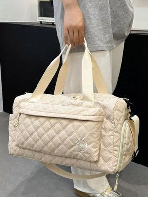 Diamond-quilted travel bag in off-white with versatile straps and front pocket detail.