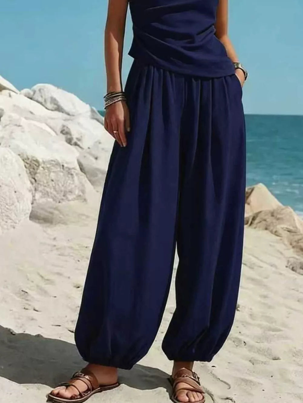 Navy one-shoulder top and wide-leg pants set with pockets, styled casually on the beach.
