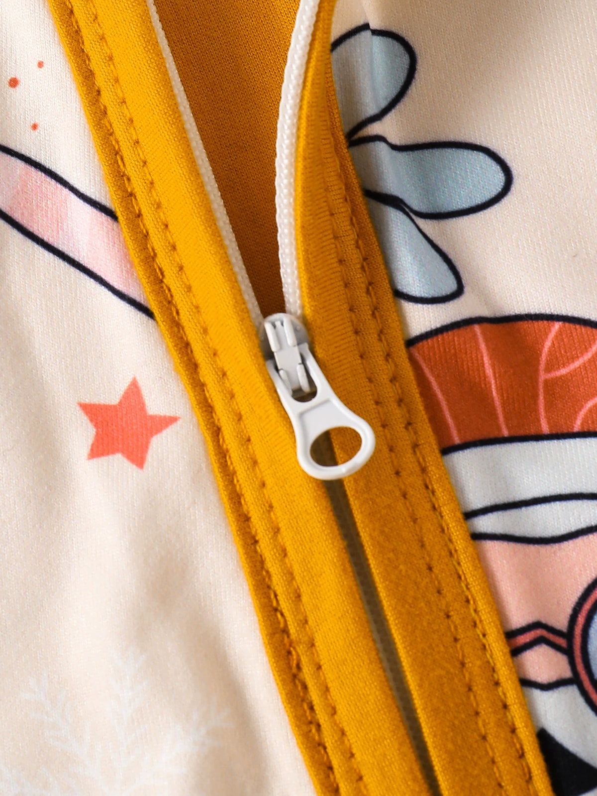 Baby one-piece with playful holiday print and yellow zipper detail.