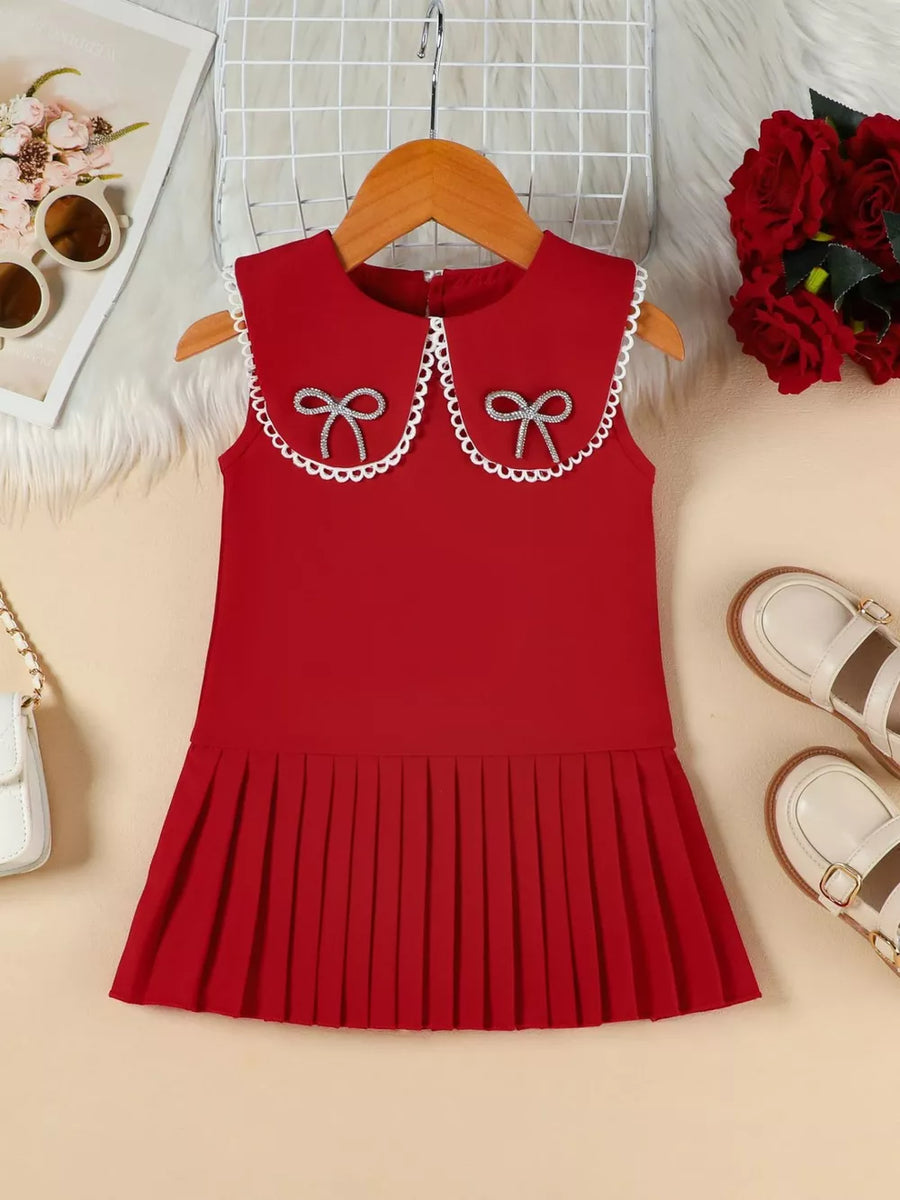 Red toddler dress with Peter Pan collar, lace trim, two bow details, and pleated skirt.