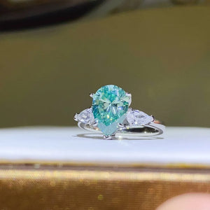 Silver ring with a large teardrop moissanite and two pear-cut stones.