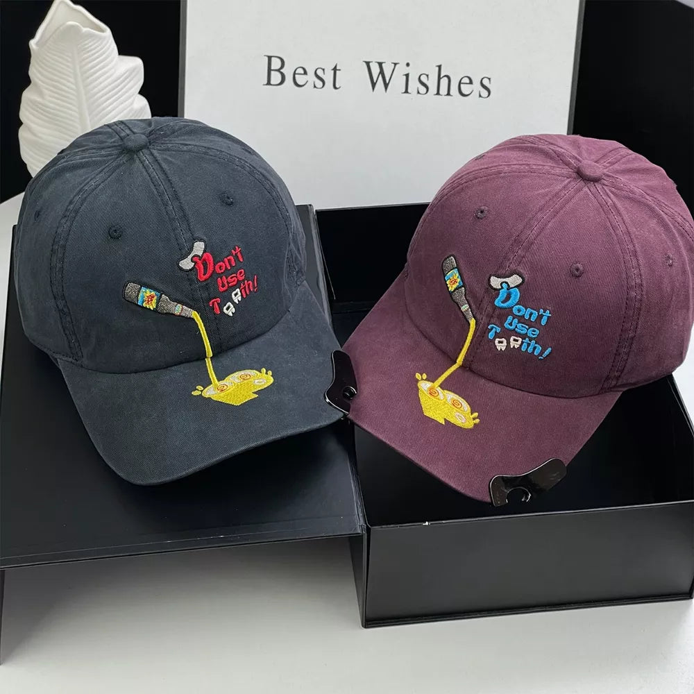 Baseball cap in deep purple with embroidered cartoon and text detail.