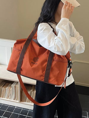 Large orange plaid Oxford travel bag with brown trim and adjustable strap.